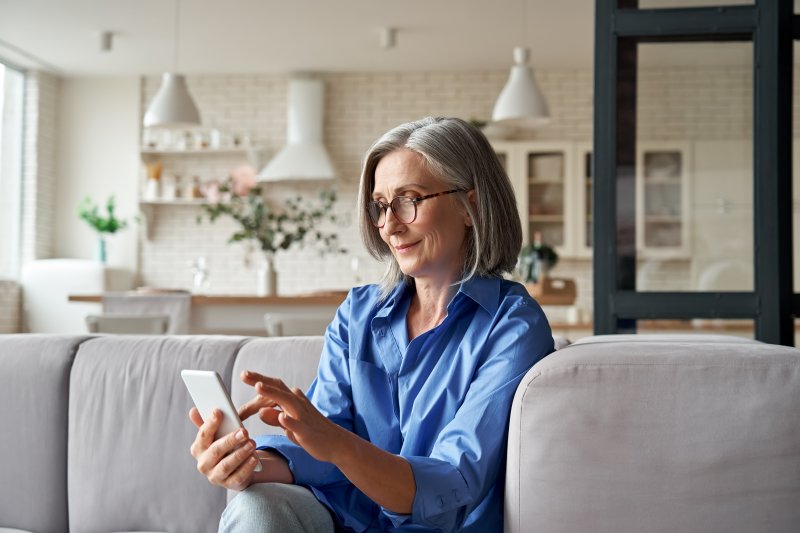 Woman reviewing denture adhesives in Van Nuys on her phone