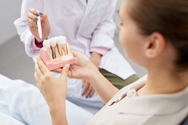 Woman holding a model of dental implants.