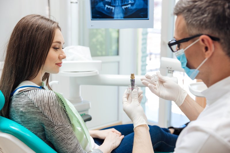 A dentist explaining the dangers of getting dental implants for cheap